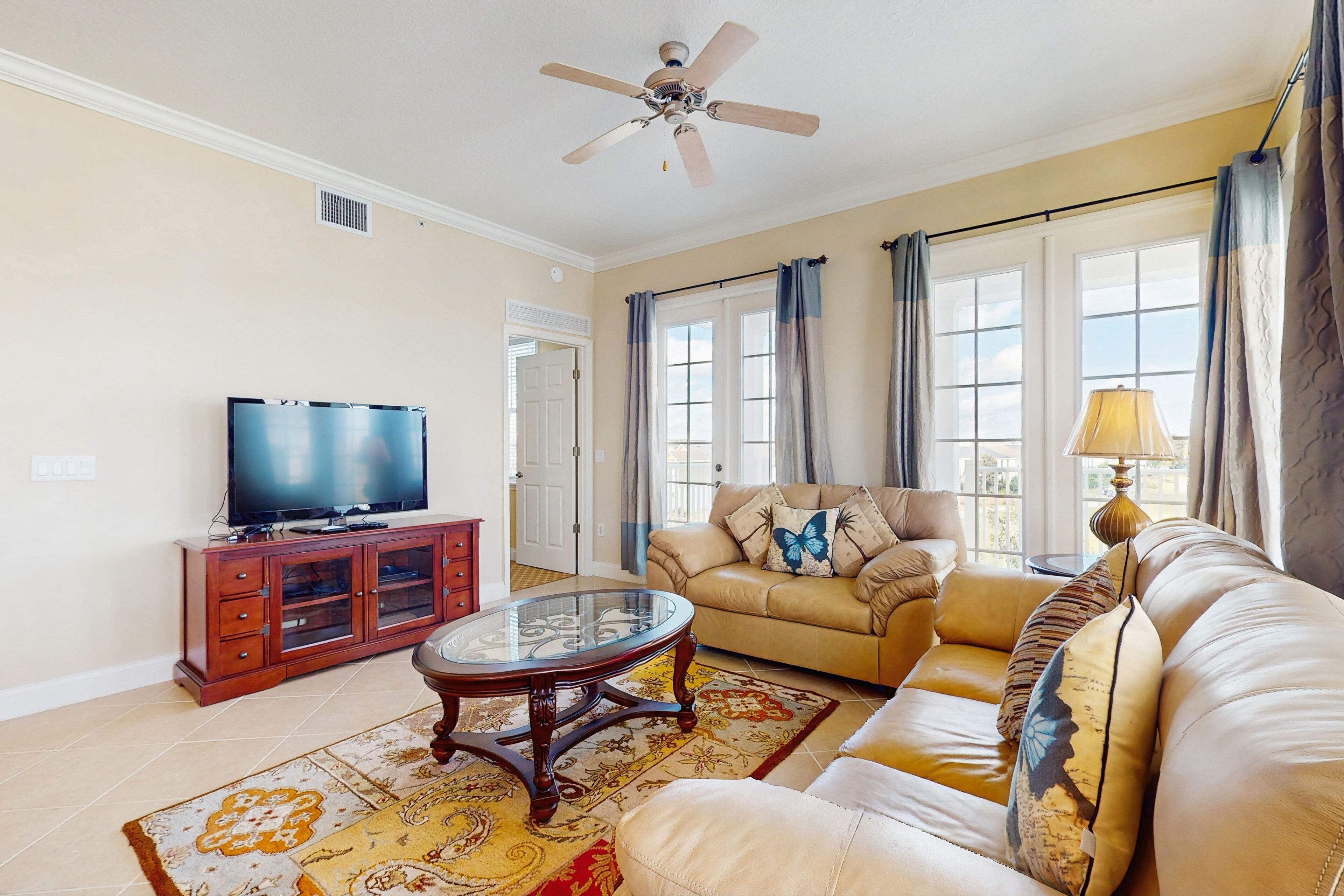 A living room with a television, sofa, and a ceiling fan.