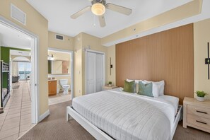 Ein Schlafzimmer mit einem Bett, Nachttischen, einem Deckenventilator und Blick ins Badezimmer.