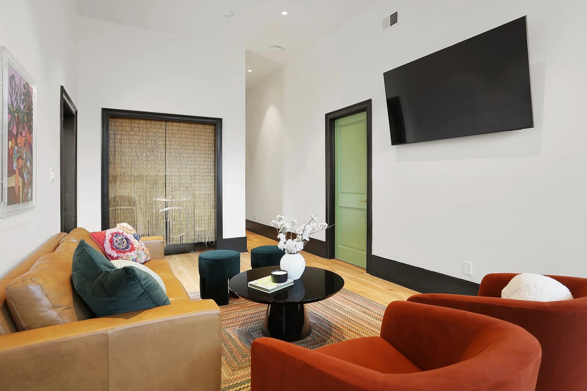 A modern living room with a sofa, armchairs, a coffee table, and a TV mounted on the wall.