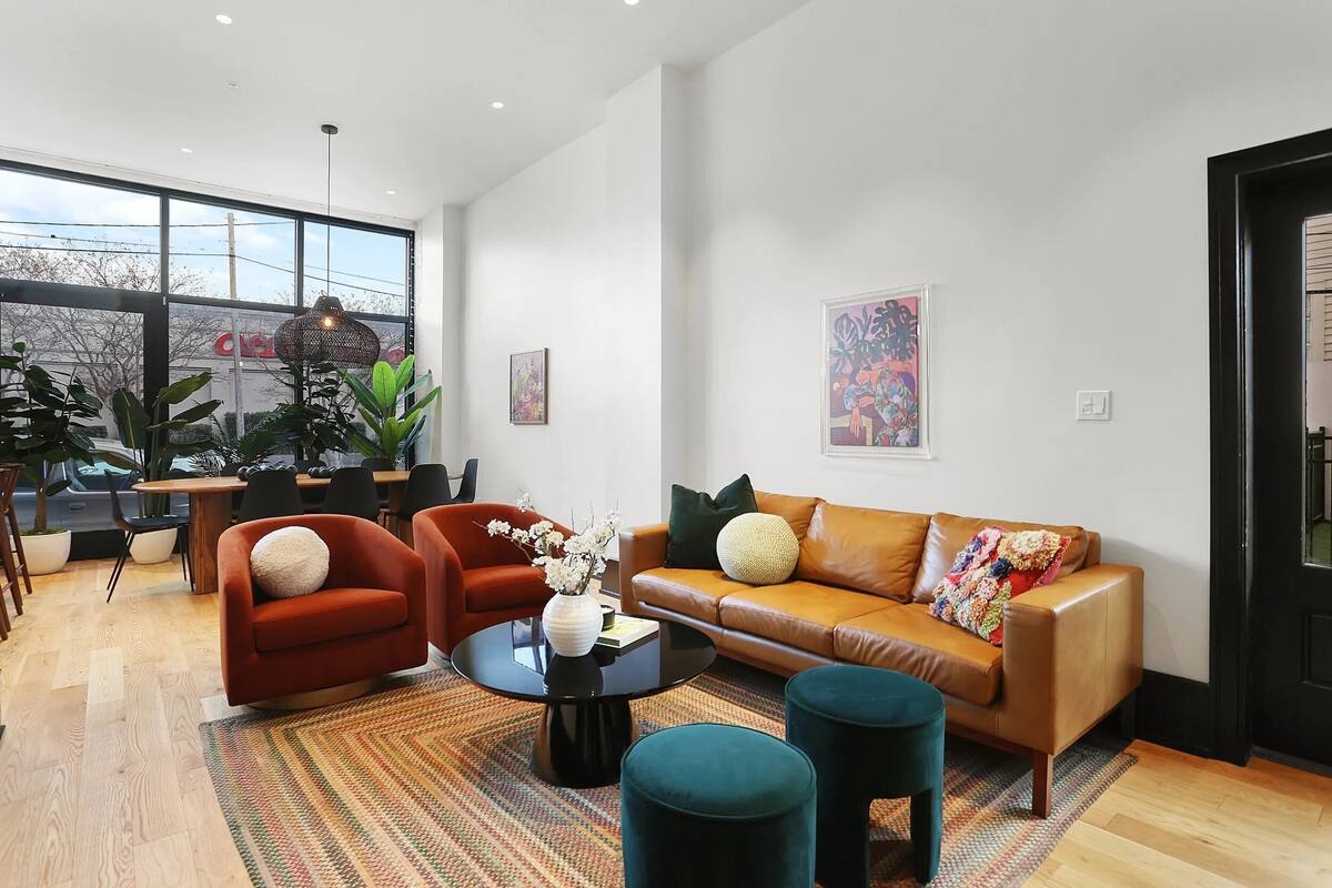 A modern living room with a leather sofa, red armchair, and a round coffee table.
