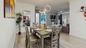 Un coin repas avec une table et des chaises en bois, une plante en pot et un luminaire suspendu moderne.