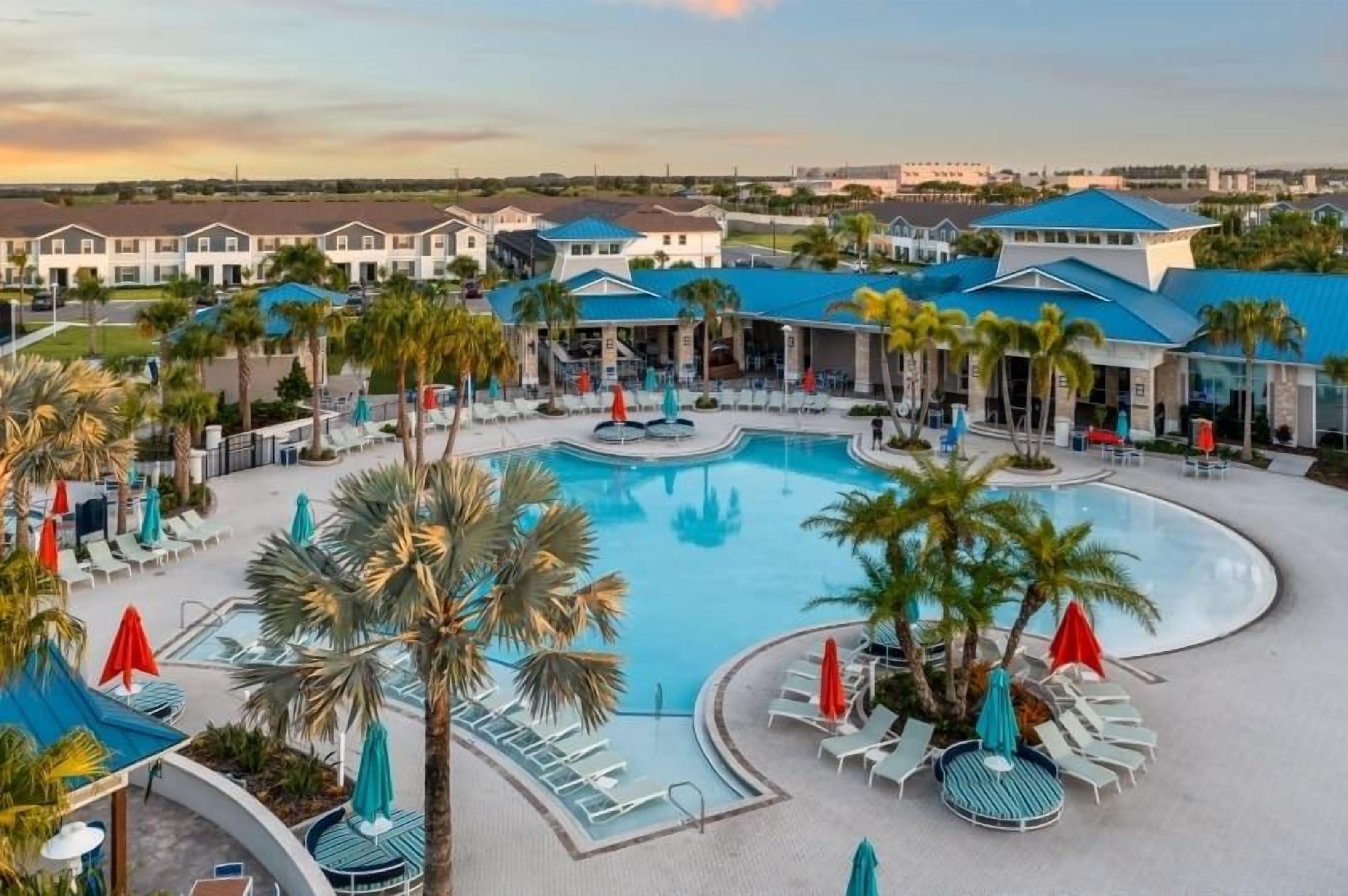A resort with a large pool, lounge chairs, and palm trees.