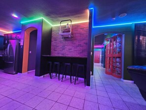 Eine Küche mit Backsteinwand, einer Bar mit Barhocker und einem Kühlschrank.