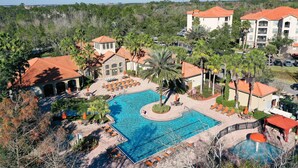 A resort with a large swimming pool, lounge areas, and multiple buildings with red-tiled roofs. - Resort condo with heated pool, gym, BBQ area, balcony, W/D, children's pool, AC (Davenport)