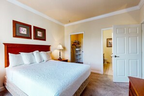 A neatly arranged bedroom with a large bed, a bedside table with a lamp, and a wardrobe. - Resort condo with heated pool, gym, BBQ area, balcony, W/D, children's pool, AC (Davenport)