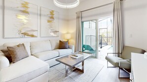 A modern living room with a white sofa, a glass coffee table, and a chandelier. - Modern Townhouse with Private Pool Near Disney & Top Attractions (Davenport)