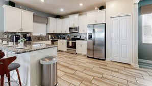 Una cocina moderna con gabinetes blancos, electrodomésticos de acero inoxidable y encimera de granito.