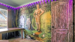 Ein Zimmer mit einer Wandmalerei von Star Wars Figuren, einer Holztür und einer Bank.