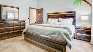 Ein Schlafzimmer mit einem hölzernen Bett, einem Nachttisch, einer Kommode und einem großen Spiegel.