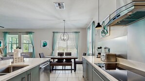 A modern kitchen with a central island, a dining area, and a built-in oven. - Dog-friendly ground-floor home in gated community w/lake views & enclosed patio (Davenport)