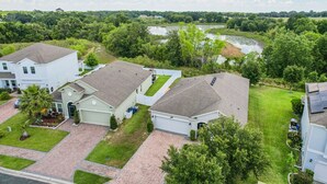 A residential area with houses, a driveway, and a river in the background. - Dog-friendly ground-floor home in gated community w/lake views & enclosed patio (Davenport)