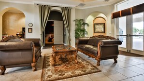 A spacious lobby with a classic design, featuring leather sofas, a glass-top coffee table, and a large rug. - Updated retreat with pool access, W/D, AC, & patio - close to Disney Parks (Kissimmee)