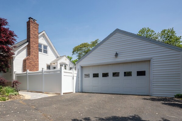 A single-story house with a garage, a brick chimney, and a white fence. - Cozy Cottage with Fire Pit (Fairfield)