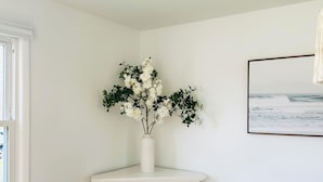 Een eetruimte met een houten tafel, witte stoelen, een witte open haard en een aan de muur bevestigd schilderij.
