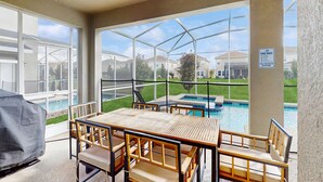 A covered patio area with a pool view, outdoor seating, and a grill. - Spacious family villa with private pool, spa and movie loft (Kissimmee)