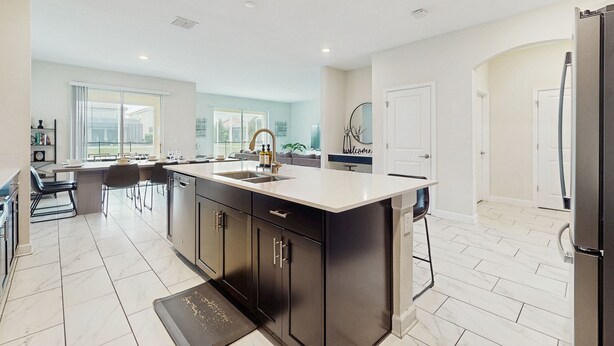 A modern kitchen with a large island, dark cabinetry, and a light-colored countertop. - Spacious family villa with private pool, spa and movie loft (Kissimmee)
