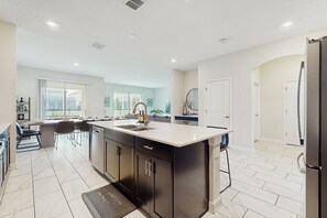 A modern kitchen with a large island, dark cabinetry, and a light-colored countertop. - Whistling Straits 6BR/5BA Davenport Home w/ Pool (Kissimmee)