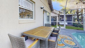 A covered patio with a pool, wicker furniture, and a patterned rug. - Radiant retreat with private pool,  on-site golf, board games, AC, & W/D (Haines City)