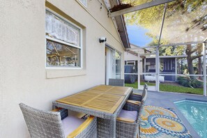 A covered patio with a pool, wicker furniture, and a patterned rug. - Radiant retreat with private pool,  on-site golf, board games, AC, & W/D (Haines City)