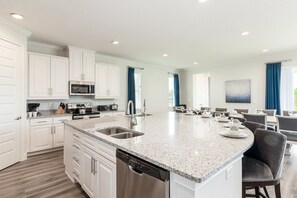 Una cocina moderna con armarios blancos, encimera de granito y electrodomésticos de acero inoxidable.