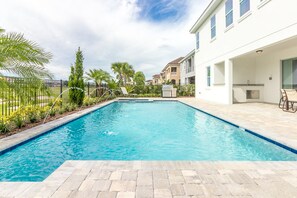 A swimming pool with a tiled deck, surrounded by a fence and palm trees. - 14BR/14.5BA Castle Getaway in Gated Reunion Resort (Kissimmee)