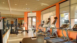 Een fitnessruimte met loopbanden, krachttoestellen en een spiegelwand.