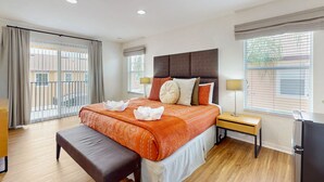 Een hotelkamer met een groot bed, een bankje, een bureau en een koelkast.