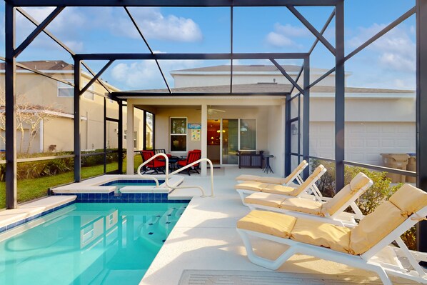Une piscine extérieure couverte, dotée de chaises longues et d’un espace patio.