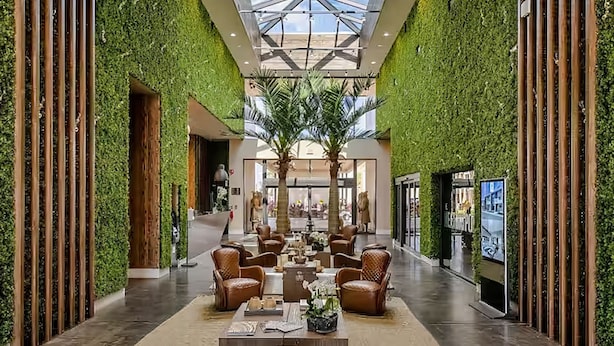 A spacious lobby with a high ceiling, green walls, and a central seating area with leather chairs and tables. - Modern villa with patio, grill, central AC, WiFi, shared pool, tennis, & gym (Kissimmee)