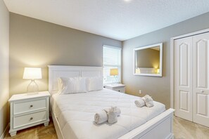 Une chambre à coucher comprenant un lit, des tables de chevet, une lampe, un miroir et une armoire.