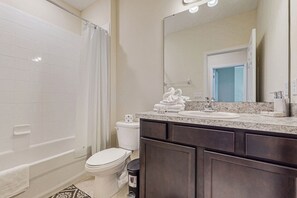 Ein Badezimmer mit Badewanne, Toilette, Waschbecken und dunklen Holzausbau.