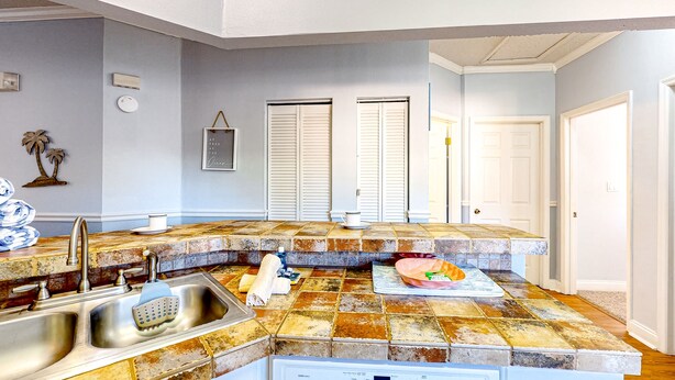 A kitchen with a granite countertop, stainless steel sink, and a dishwasher. - Sunny condo with pool, hot tub, tennis court, & gym - balcony & washer/dryer (Kissimmee)