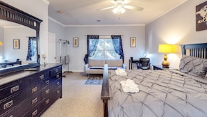 A bedroom with a bed, dresser, mirror, ceiling fan, window with curtains, and a lamp. - Sunny condo with pool, hot tub, tennis court, & gym - balcony & washer/dryer (Kissimmee)