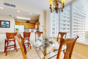 A dining area with a glass table, wicker chairs, and a chandelier. - Lakefront retreat near attractions with lake view, AC, kitchen, pool & hot tub (Orlando)