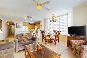 A spacious living room with a sofa, a coffee table with a plant, a TV, and a dining area with chairs and a table. - Lakefront retreat near attractions with lake view, AC, kitchen, pool & hot tub (Orlando)