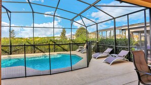 A glass-enclosed pool area with lounge chairs and a clear view of the surrounding landscape. - Modern Family Home - Private Pool, Lanai, WiFi, Central AC & Washer-Dryer (Davenport)