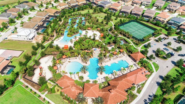 Vue aérienne d’un quartier résidentiel doté d’une piscine centrale, de courts de tennis et d’un parc aménagé.
