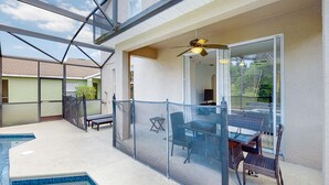 Un espacio al aire libre cubierto con piscina, barandilla de vidrio y una mesa con sillas.