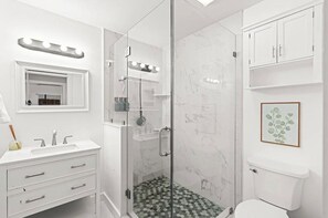 A modern bathroom with a glass-enclosed shower, a vanity with a mirror and lights, and a toilet. - Fabulous 3-bedroom house in sunny Jupiter (Jupiter)
