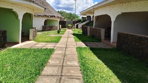 Um caminho leva a uma fileira de casas de campo com telhados de palha, paredes de pedra e portas verdes.