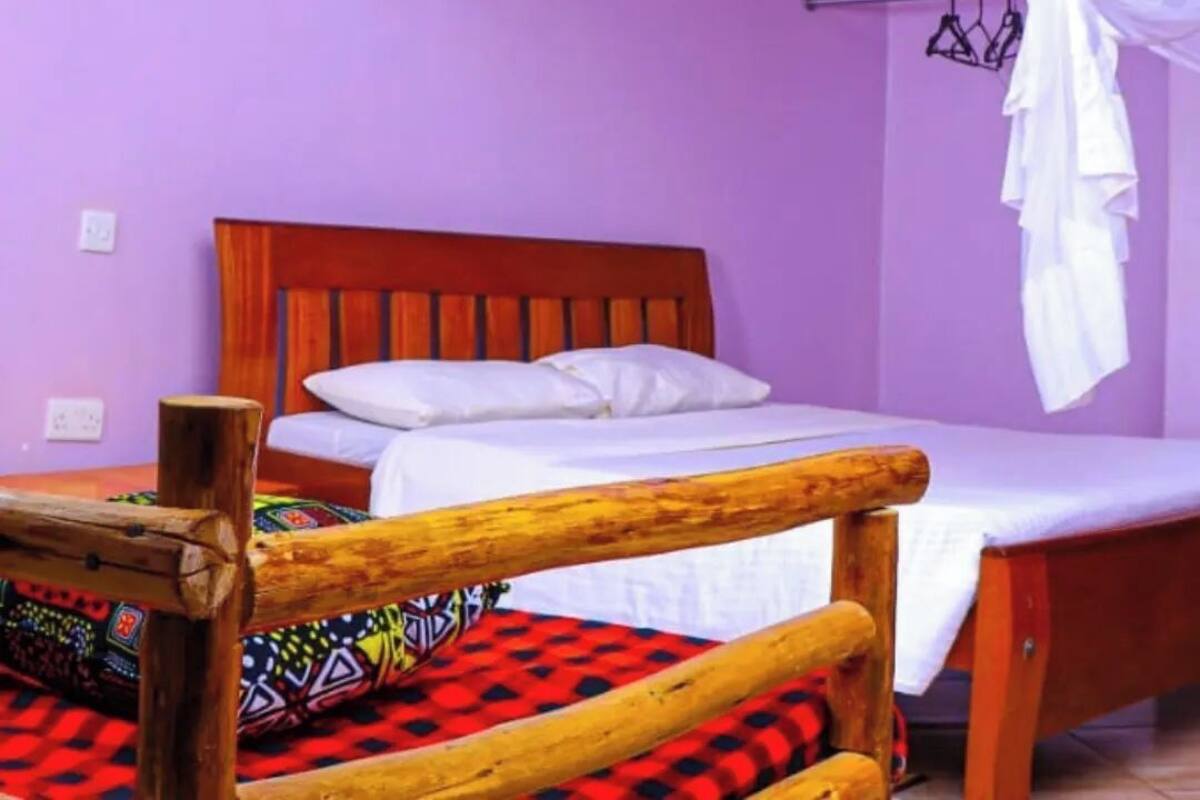 A room with a wooden bed frame, a white canopy, and a colorful patterned bedspread.