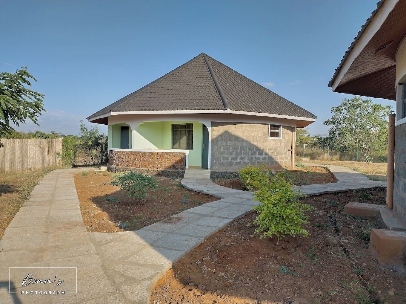 A single-story house with a sloped roof, a front porch, and a small front yard with a pathway leading to the entrance.