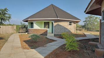 A single-story house with a sloped roof, a front porch, and a small front yard with a pathway leading to the entrance.