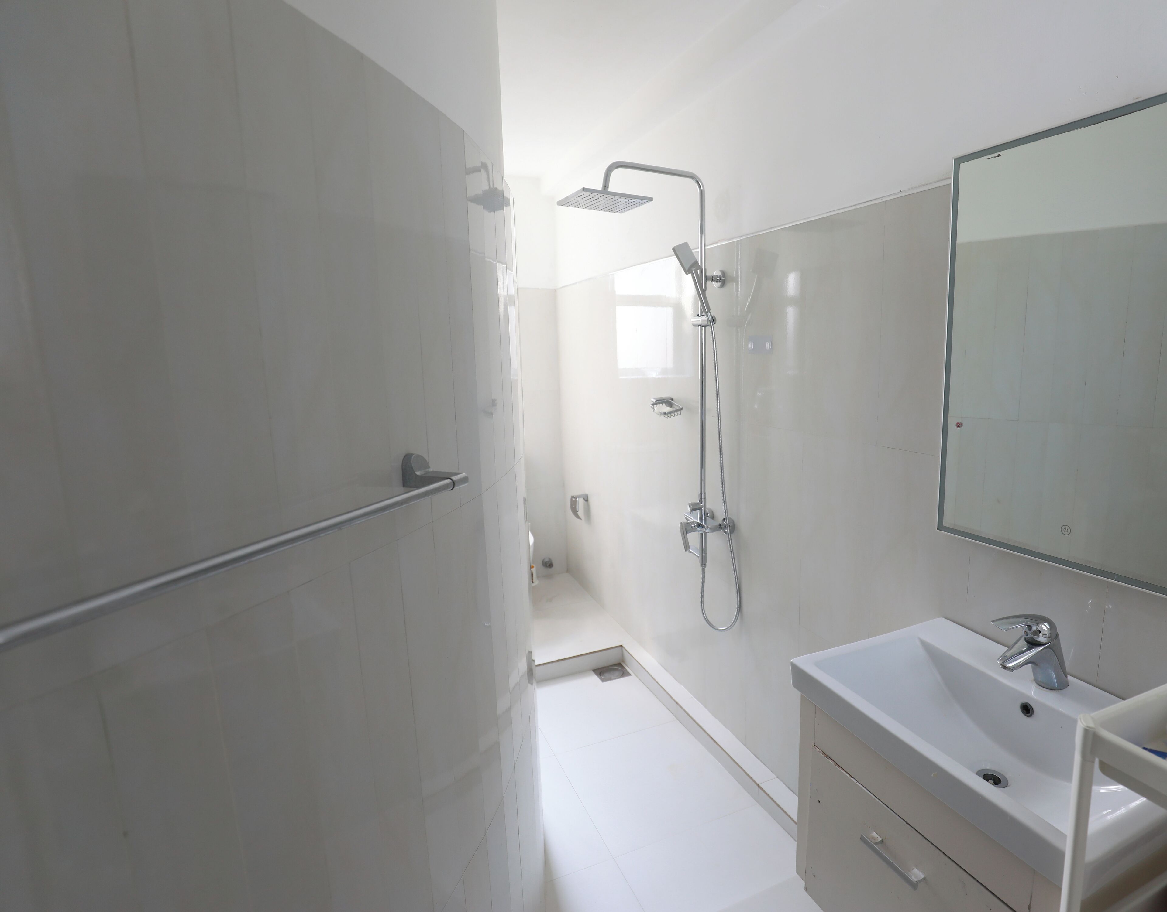 Een moderne badkamer met douche, wastafel en spiegel.