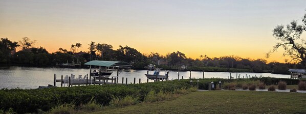 Une jetée au bord du lac avec des bateaux, un espace de repos couvert et une zone herbeuse délimitée par une clôture.