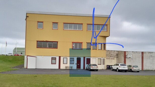Un edificio a più piani con tetto piatto, una porta rossa e un cartello con la scritta "MARKADUR".