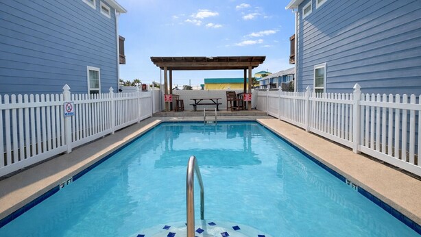 A swimming pool with a wooden deck and a covered seating area. - GS6 Shared Heated Pool, Walk to the Beach, Golf Cart Access (Port Aransas)