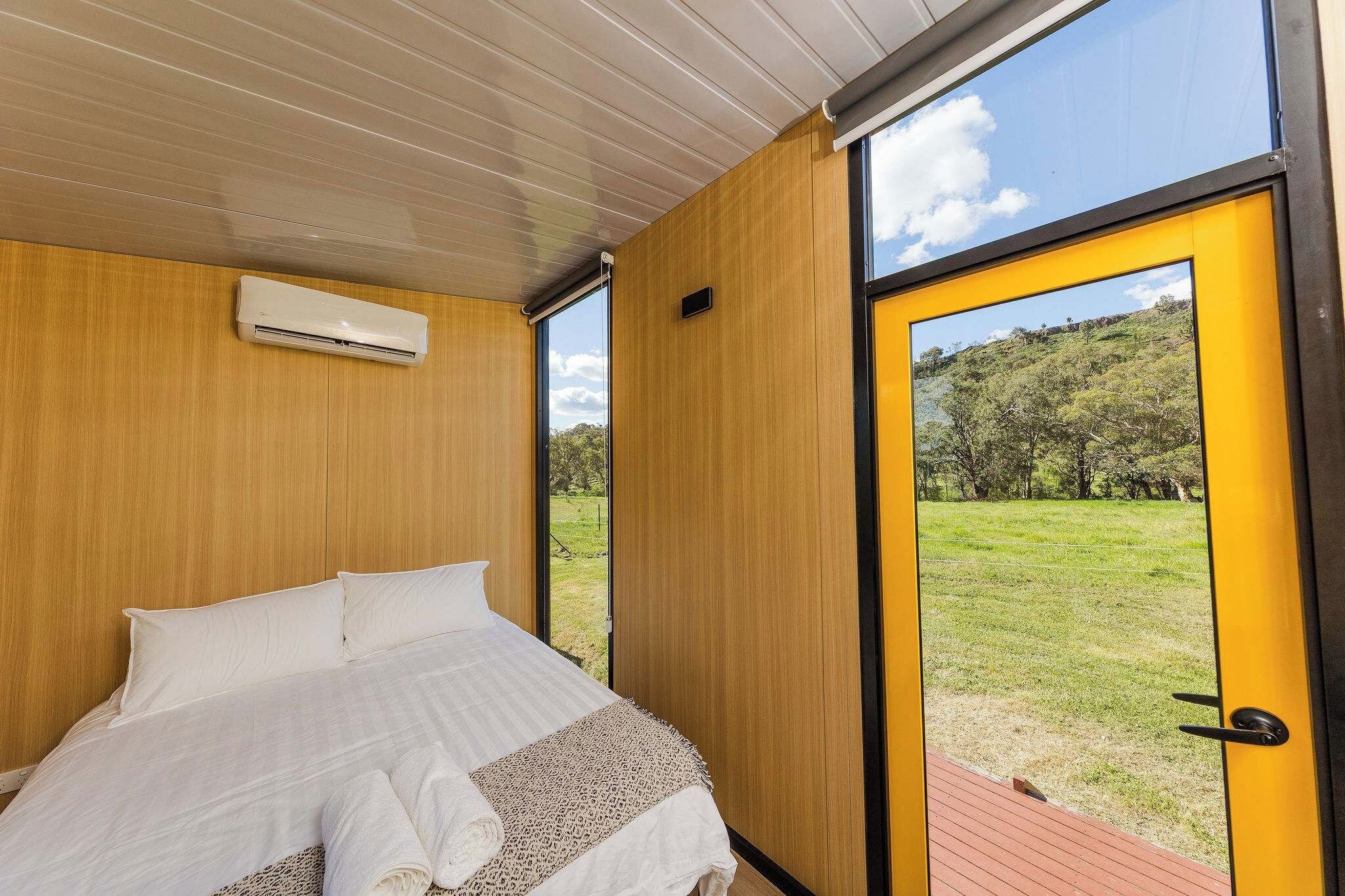 Een slaapkamer met een bed, een airconditioning en een deur naar een buitenruimte.