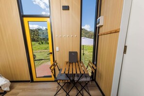 A room with a wooden door, a small table, two chairs, and a bench.