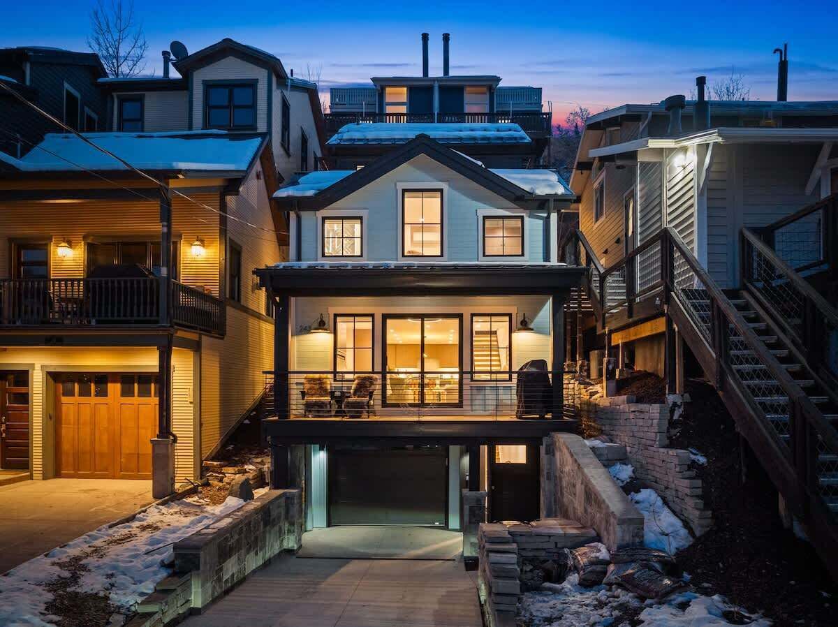 Ein zweigeschossiges Haus mit verdeckter Veranda, Garage und einer Treppe, die zu einem Balkon im zweiten Stock führt.